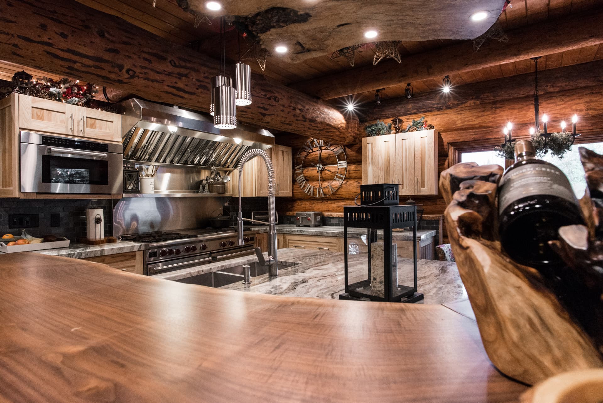 Rustic log-cabin kitchen with a professional range, live-edge counter and timber beams