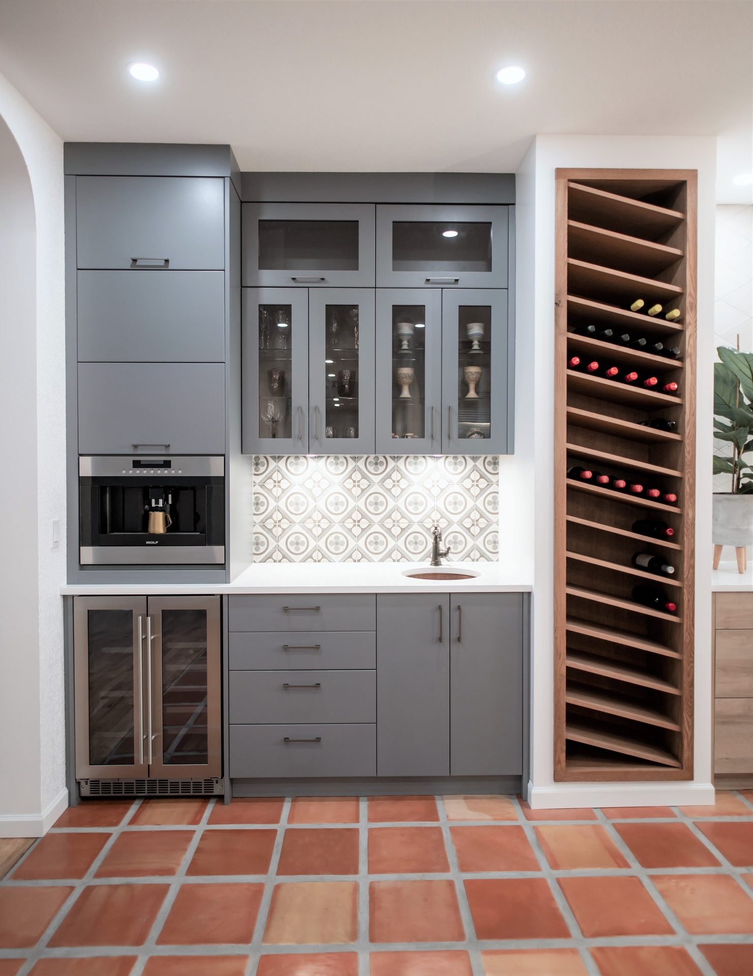 Custom wet bar with slate-gray cabinetry, tiled backsplash and built-in wine rack
