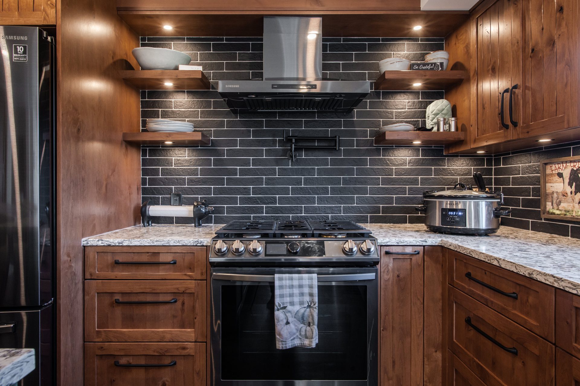 Custom kitchen with walnut cabinetry, black subway tile and floating walnut shelves